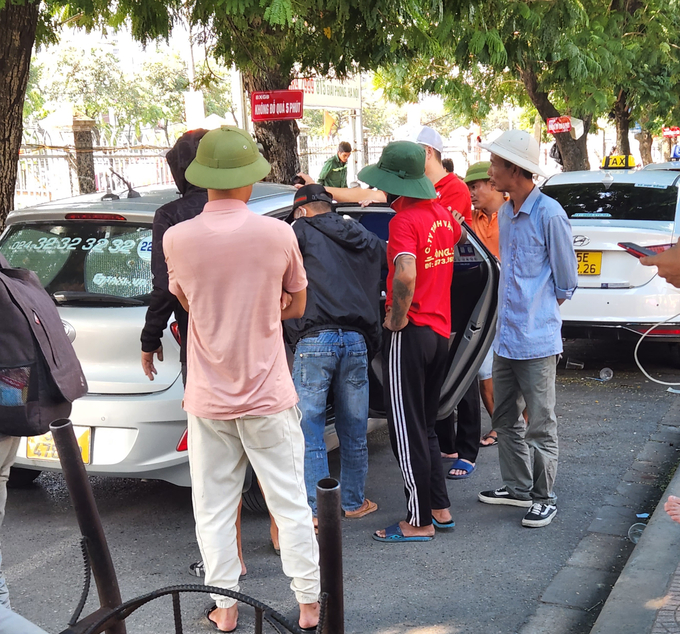 Một chiếc taxi bị nhân viên các nhà xe quây kín, khiến hành khách không thể xuống xe