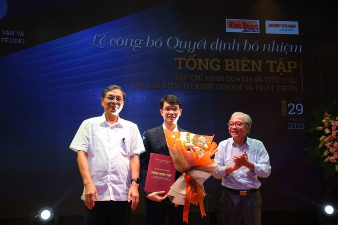 PGS.TS Đặng Văn Thanh - Chủ tịch HĐQL Viện Đào tạo, Tư vấn và Phát triển Kinh tế (IDE), và ông Nguyễn Quốc Hải - Viện trưởng Viện IDE trao quyết định và tặng hoa cho tân Tổng Biên tập Bùi Văn Khương
