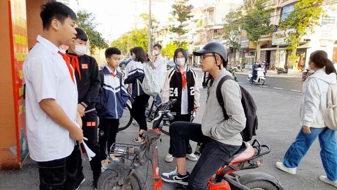 Thành viên Đội Sao đỏ Trường THCS Trần Phú tuyên truyền đến các bạn học sinh không vi phạm quy định điều khiến xe máy điện (ảnh chụp ngày 1/11)