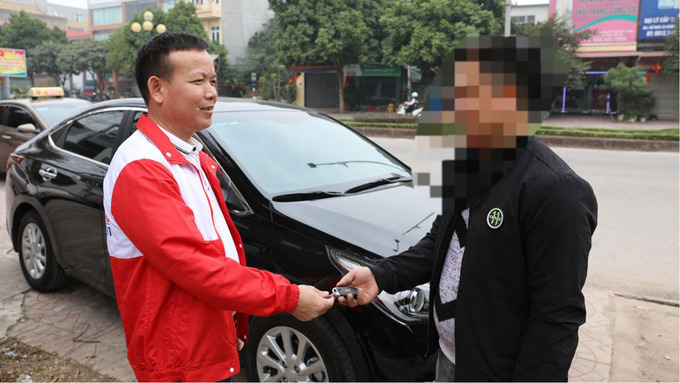Khách hàng (bên phải) trao chìa khóa xe ô tô cho lái xe dịch vụ 'Một xe - hai tài' để đưa về nhà.