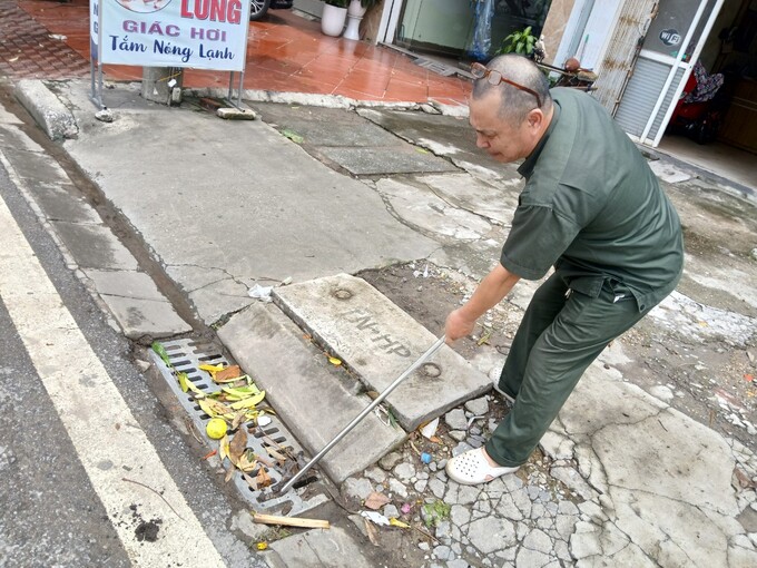 Ông Hiệu (người trong ảnh) cho biết, tuyến đường Lê Thánh Tông có nhiều xe công trình trong quá trình vận chuyển làm vương vãi nguyên vật liệu khiến cho nhiều hố ga tại đường này chứa đầy đất cát, rất khó thoát nước mưa. Ảnh: Đinh Huyền.