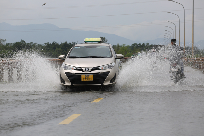 Xe taxi di chuyển với tốc độ cao khiến dòng nước bắn lên người đi xe máy